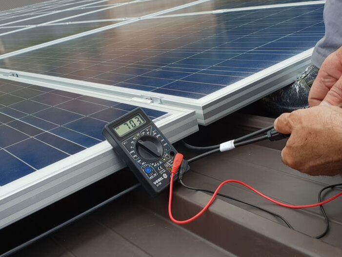 Technician testing solar panels on roof